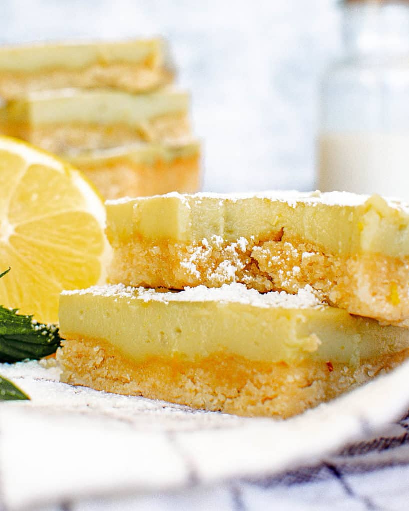 vegan gluten free lemon bars on a white plate with a bite taken out of a bar - Memorial Day potluck ideas