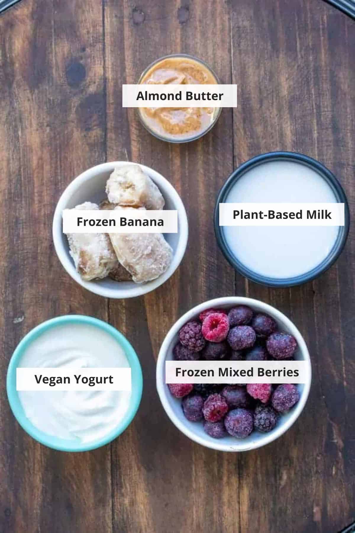 Ingredients for healthy banana berry smoothie recipe on a wood background.
