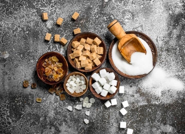 different types of sugar on gray background in brown bowls - natural sugar vs. added sugar