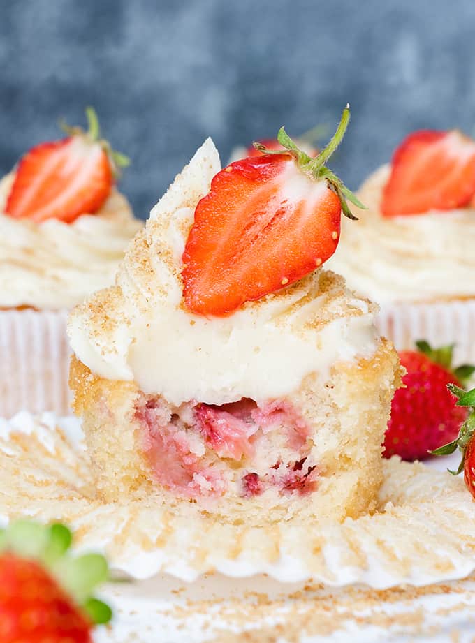 strawberry cheesecake cupcake with bite taken out topped with strawberry