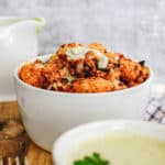 buffalo cauliflower wings with a creamy cashew vegan sauce, served in a white bowl