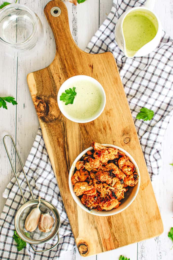 buffalo cauliflower wings with a creamy cashew vegan sauce, served in a white bowl