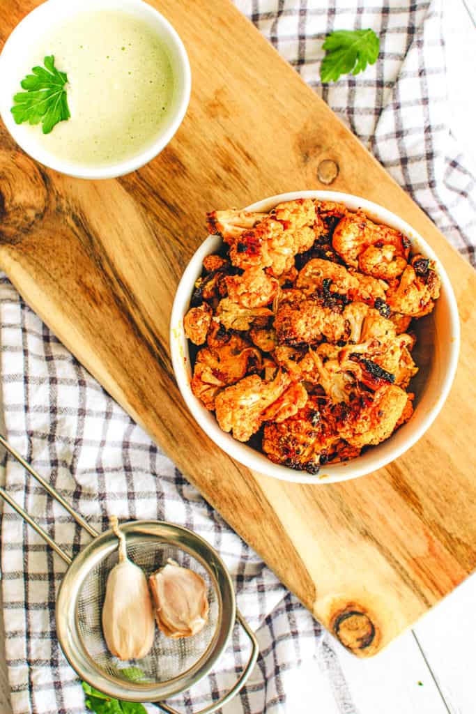 buffalo cauliflower wings with a creamy cashew vegan sauce, served in a white bowl