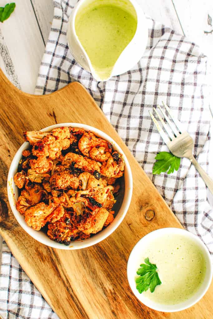 buffalo cauliflower wings with a creamy cashew vegan sauce, served in a white bowl