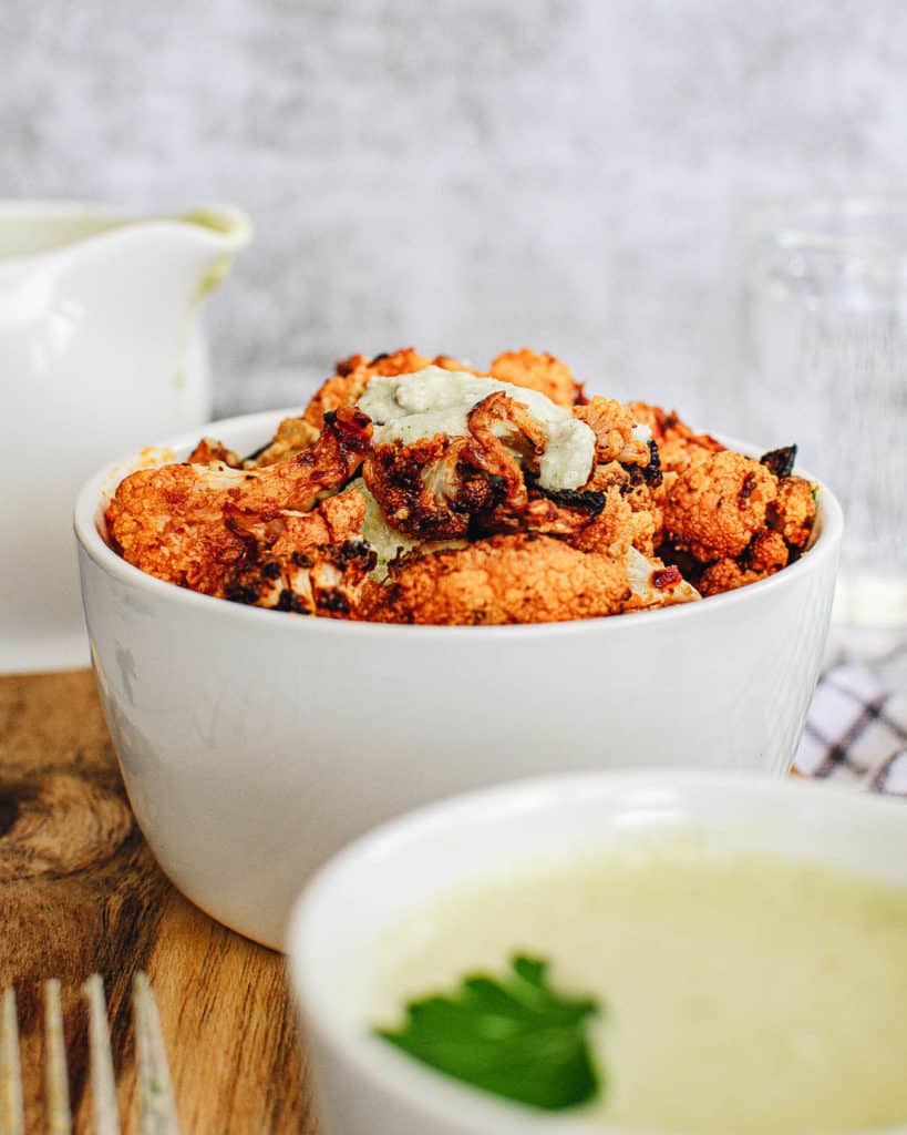 buffalo cauliflower wings with a creamy cashew vegan sauce, served in a white bowl