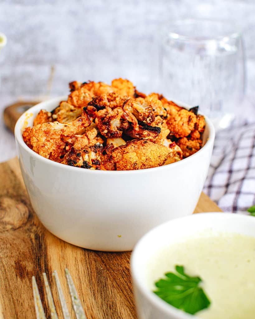 buffalo cauliflower wings with a creamy cashew vegan sauce, served in a white bowl