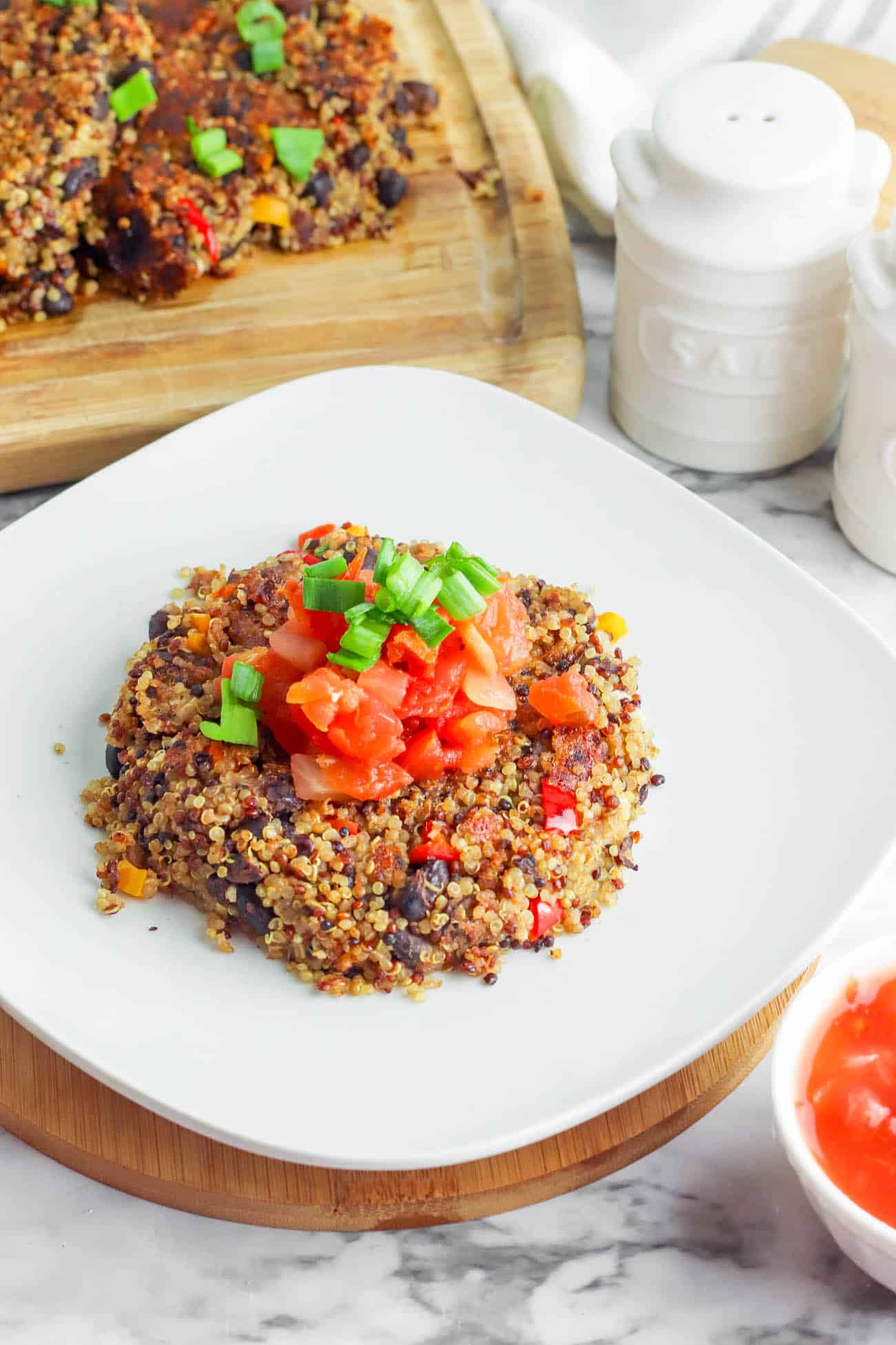 Black Bean Quinoa Cakes topped with salsa, served on a white plate