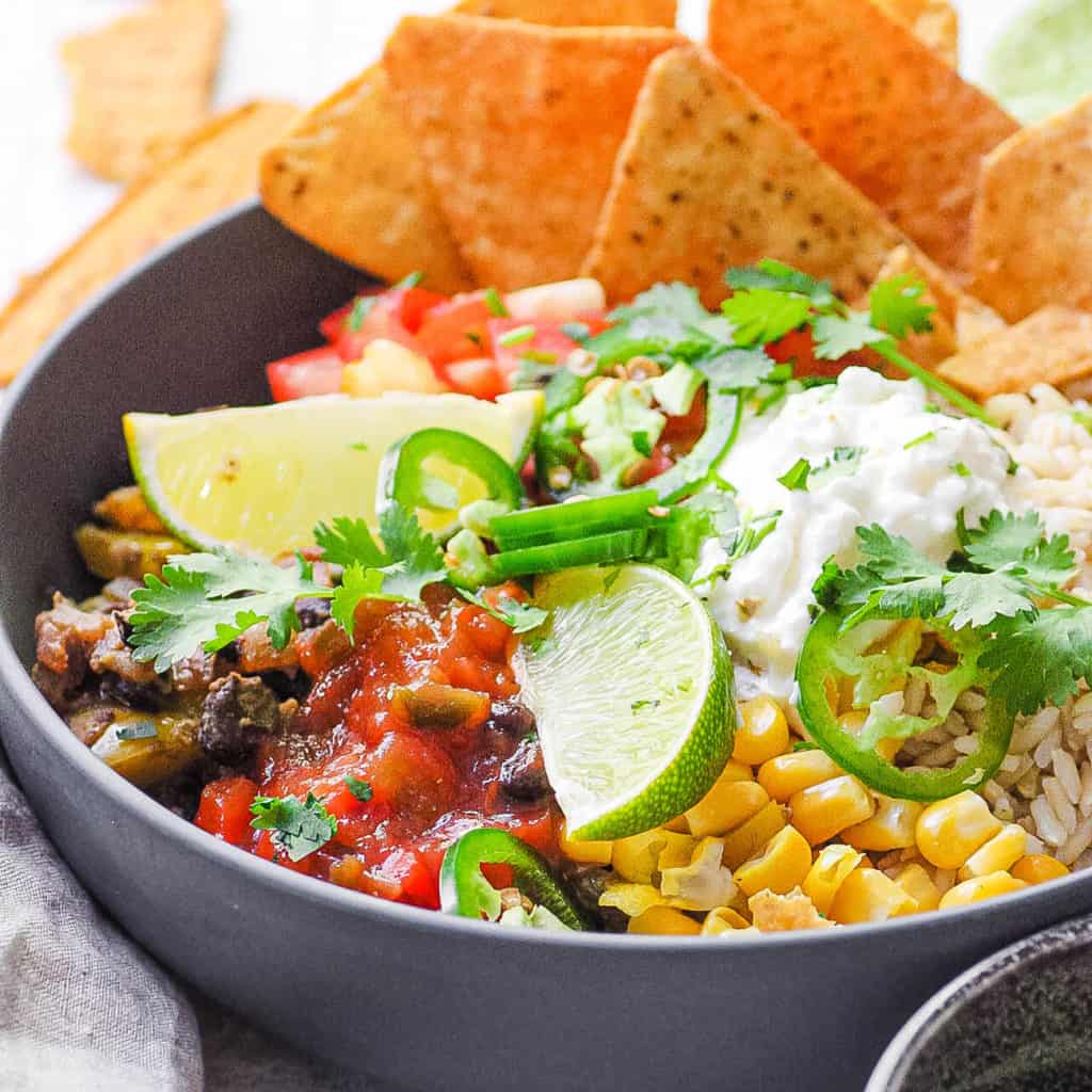 vegetarian burrito bowl with black beans, tortilla chips, corn, cheese and lime