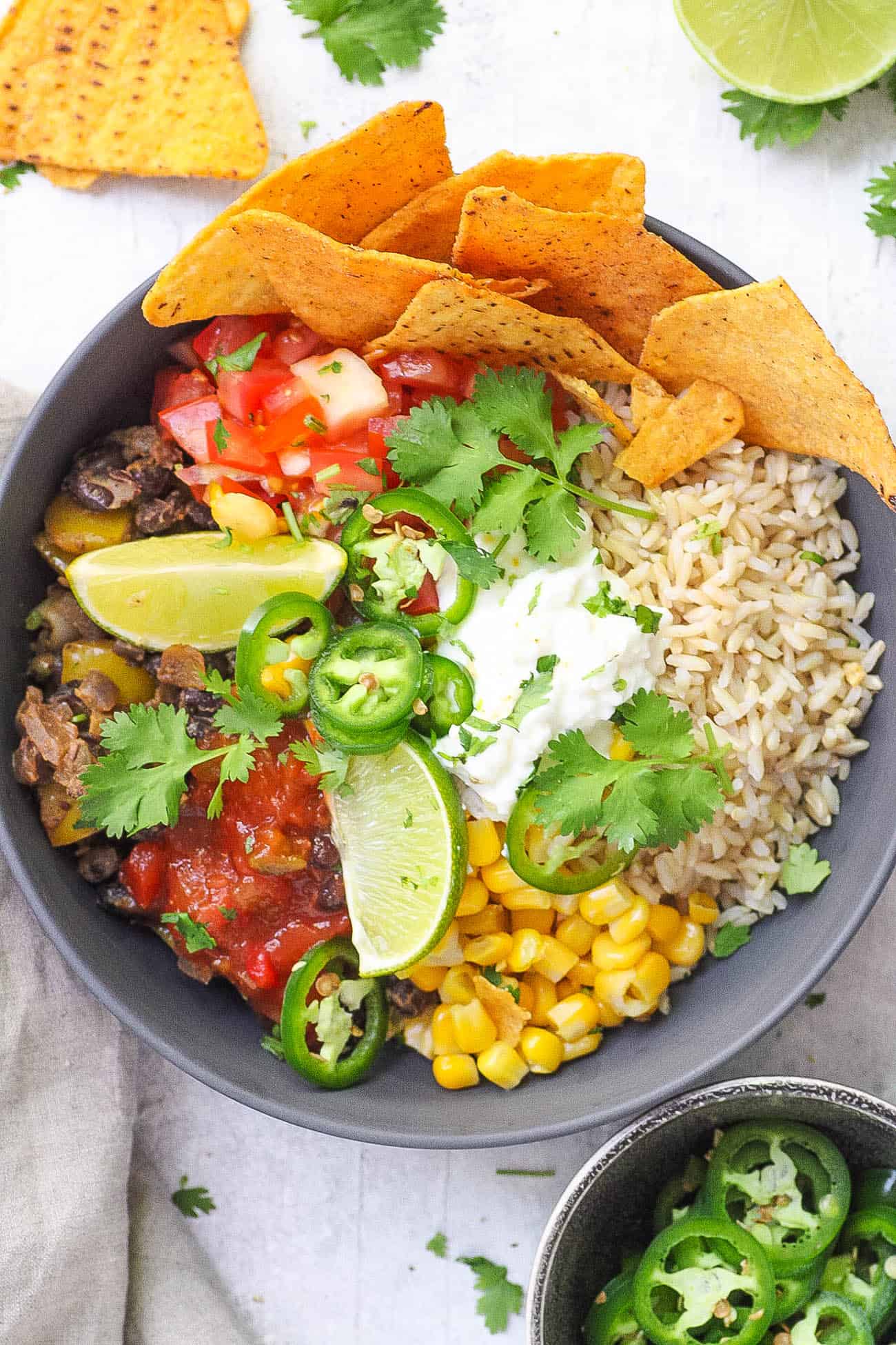 vegetarian burrito bowl with black beans, tortilla chips, corn, cheese and lime