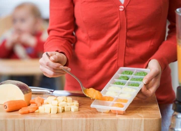 mom scooping pureed homemade baby food into ice tray