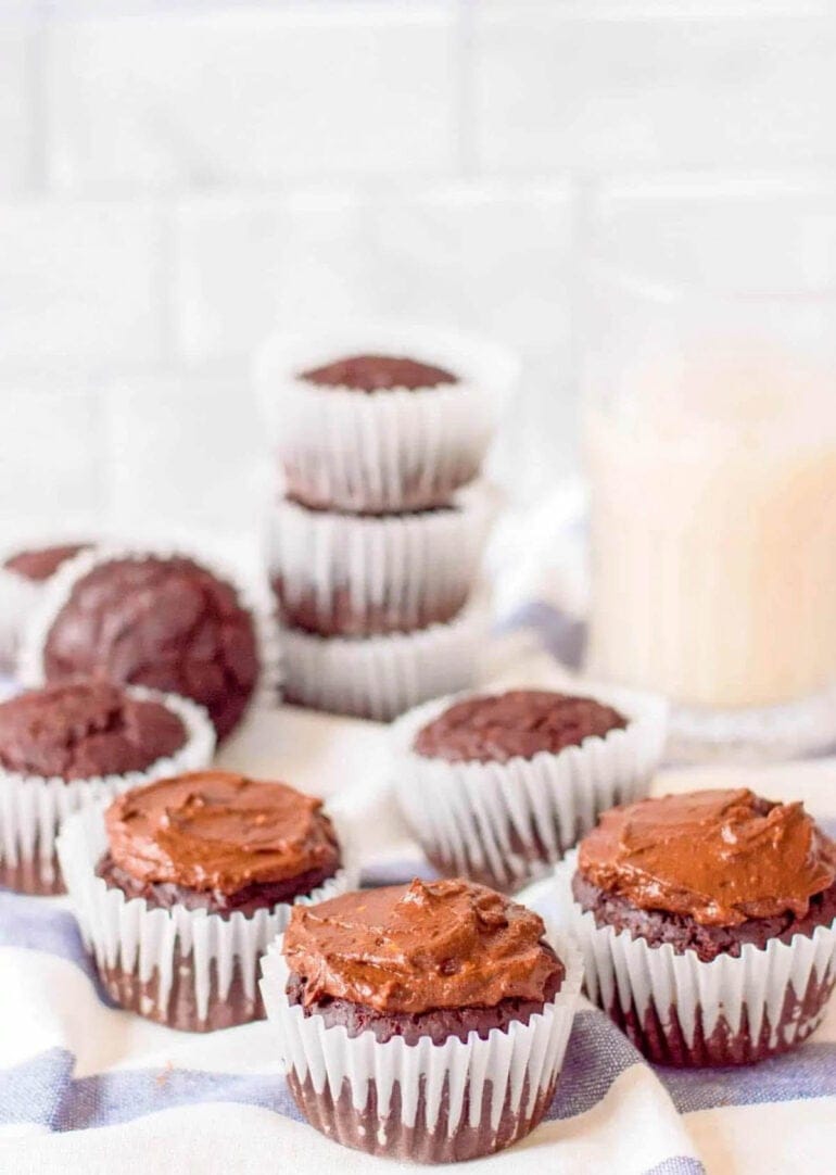 Healthy chocolate cupcakes for kids on a blue and white cloth with milk in the background.