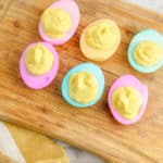 healthy deviled eggs dyed in pastel colors on a wooden cutting board