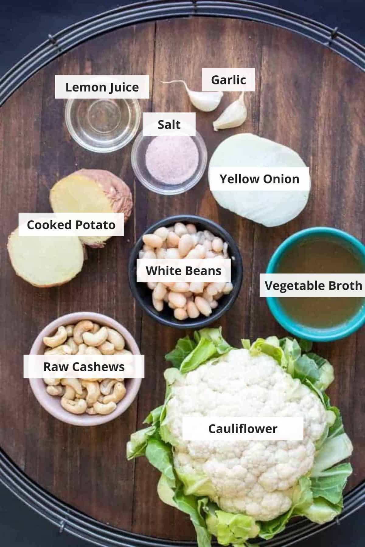 Ingredients for vegan cauliflower soup on a wood background.