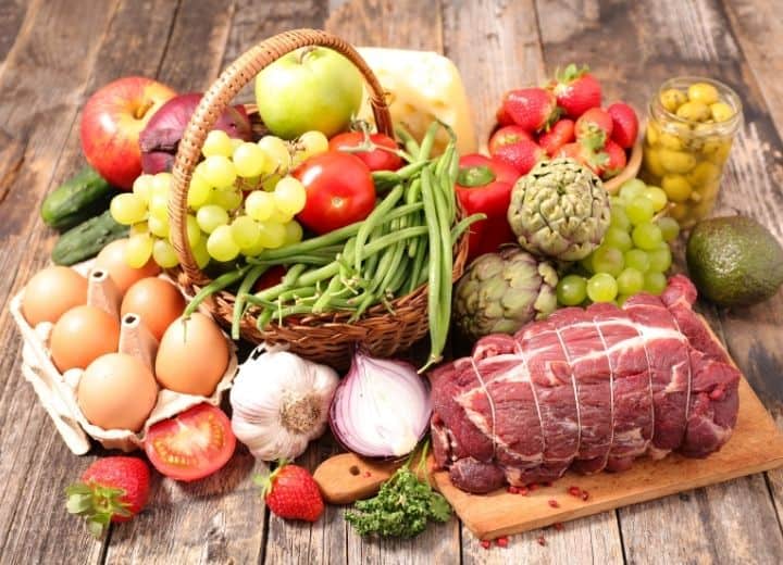 meat, produce, eggs in basket on wood table - organic foods shown for determining is organic food really better