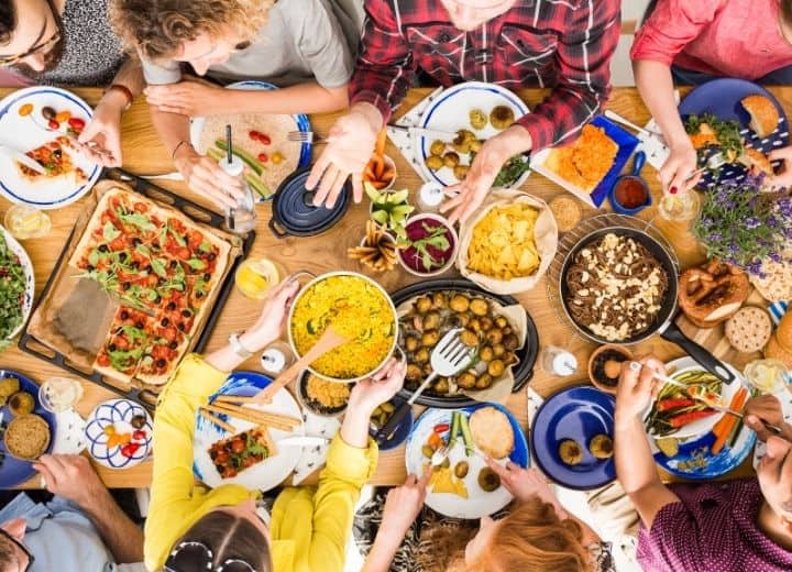 people gathered around the table with a bunch of different healthy foods to share