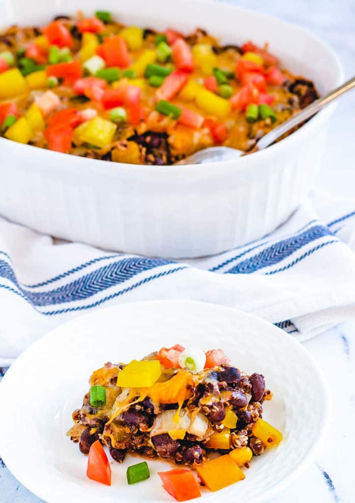 serving of black bean casserole with quinoa and cheese, in a white baking dish