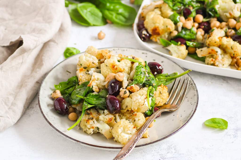 plateful of roasted cauliflower salad with spinach and chickpeas and kalamata olives