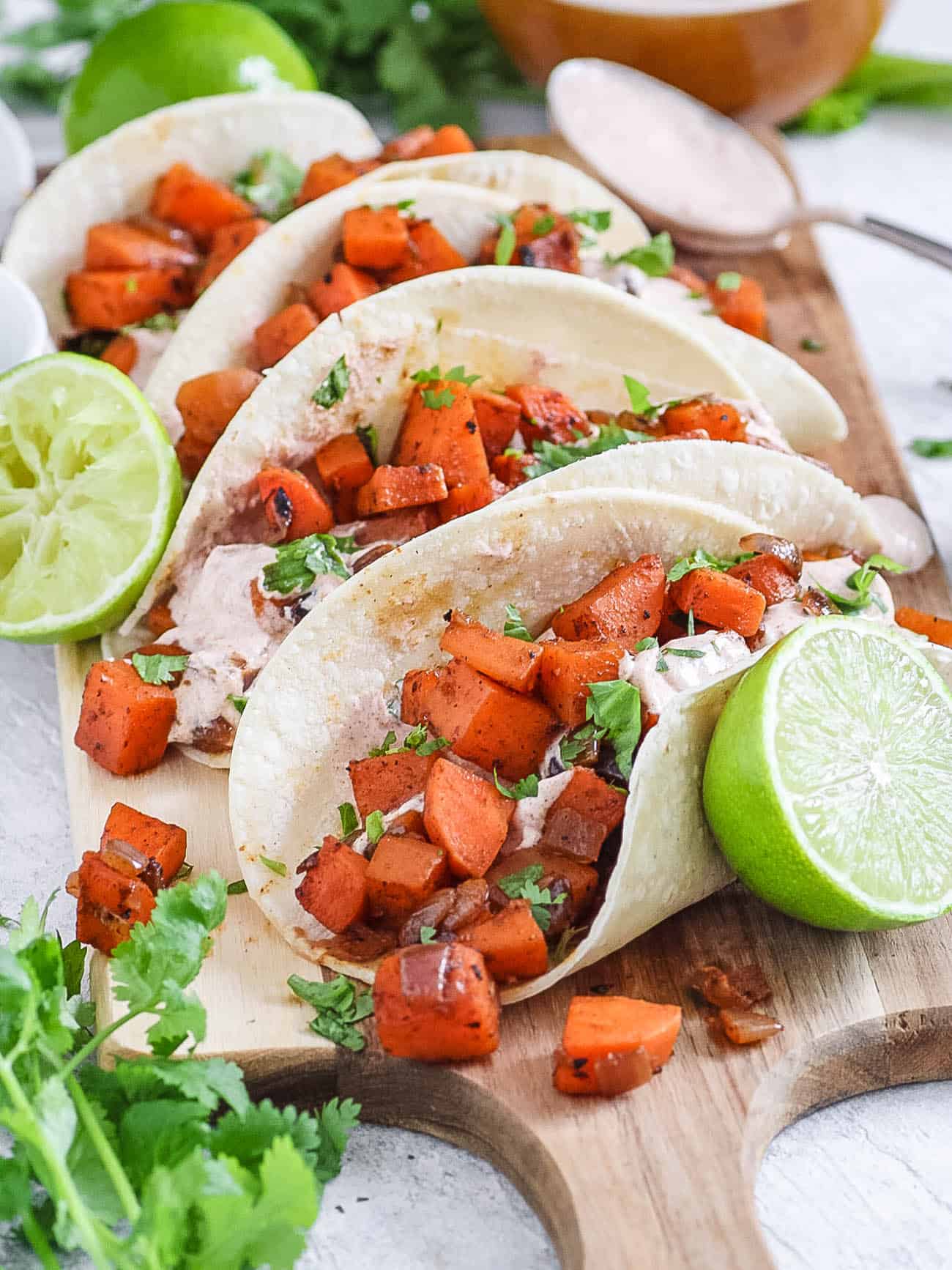 sweet potato tacos with black beans and a spicy yogurt sauce served on a wooden cutting board