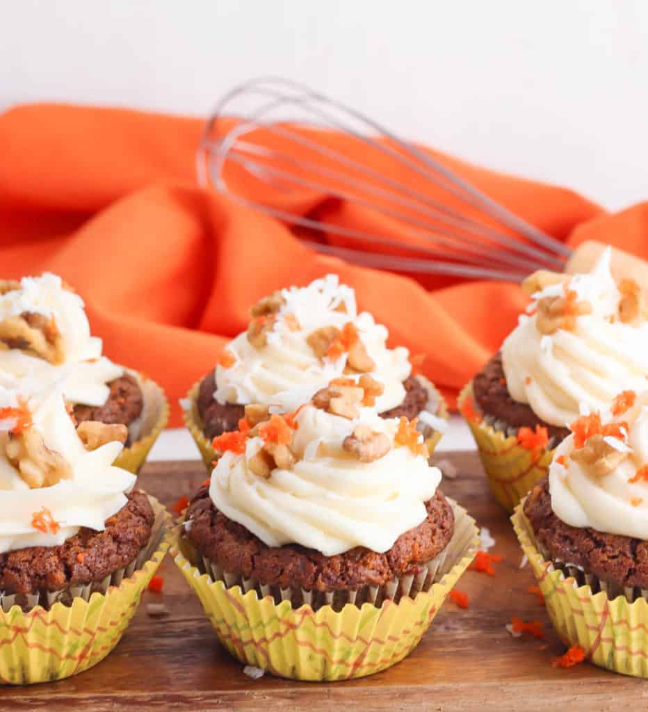 vegan carrot cake cupcakes with vegan cream cheese frosting on wooden cutting board