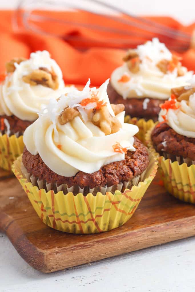 vegan carrot cake cupcakes with vegan cream cheese frosting on wooden cutting board