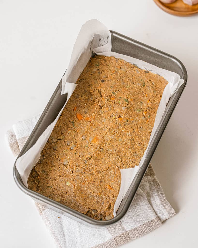 lentil loaf added to baking pan lined with parchment paper