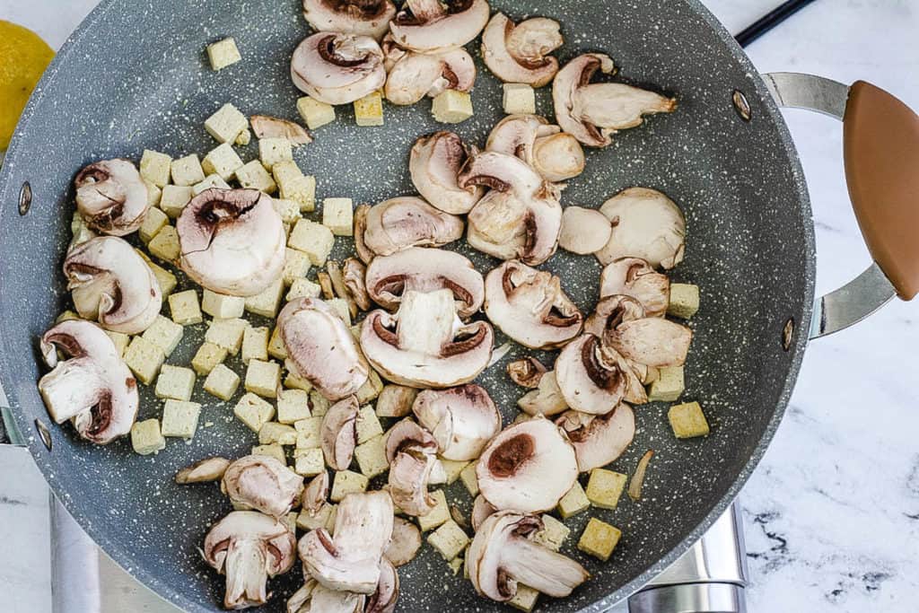 onions and mushrooms added to a pan