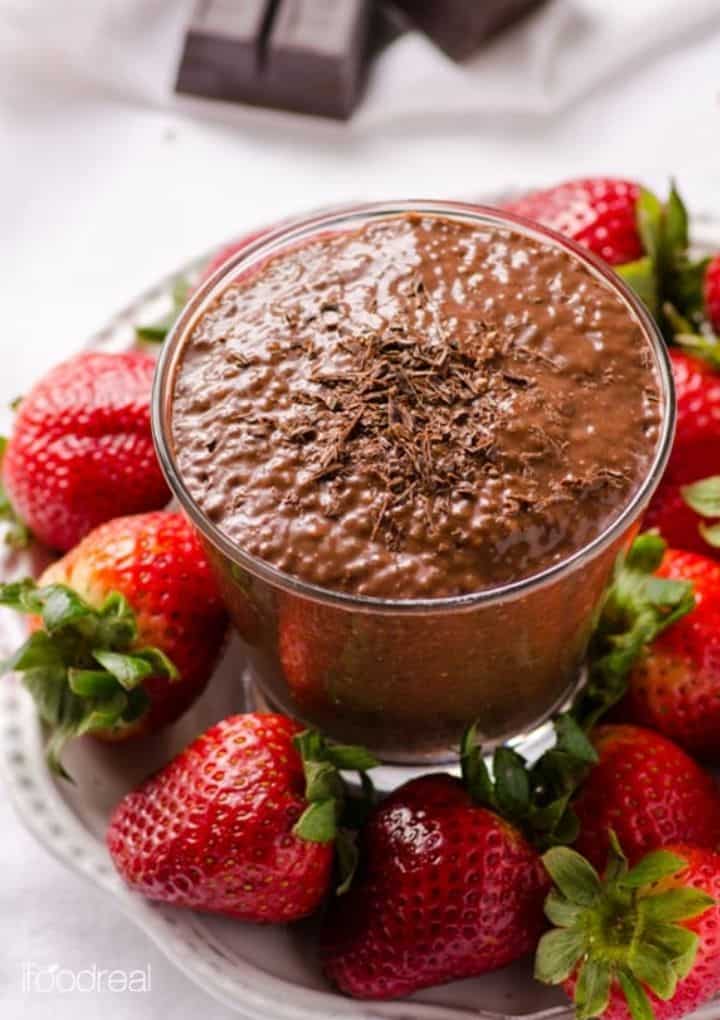 chocolate chia pudding in glass surrounded by strawberries