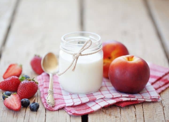 milk in jar, surrounded by strawberries, blueberries and nectarines - natural sugar vs. added sugar