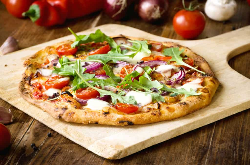 Freshly baked pizza with arugula, tomato, red onion and mozzarella - healthy pizza toppings