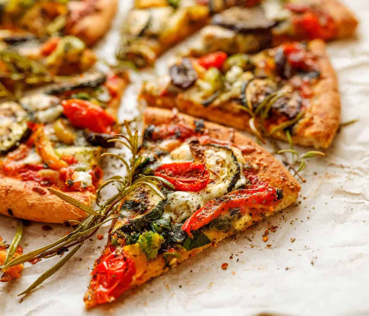 Pizza made with low fat pizza toppings like veggies and fresh herbs, served on a wooden pizza board.