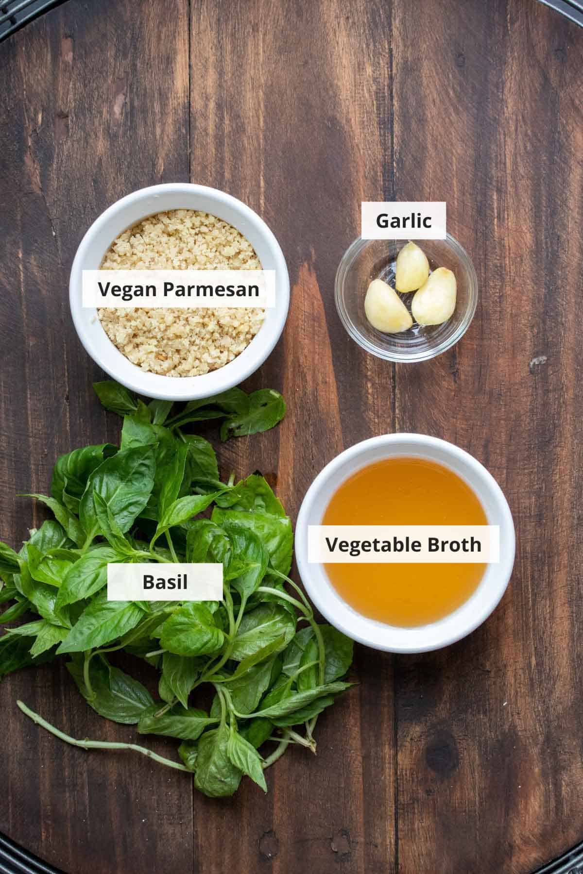 Ingredients for vegan basil pesto recipe on a wood background.