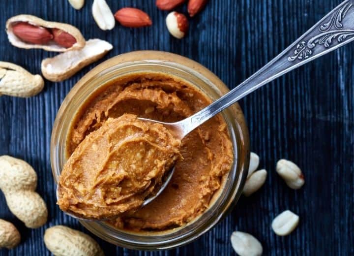 peanut butter in a jar with a spoon of peanut butter scooped out