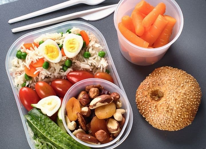 healthy plane snacks: cup of carrots, whole wheat roll, rice and vegetables, hard boiled egg, and cup of nuts