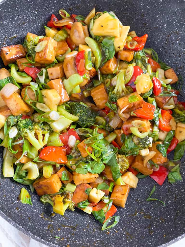 tofu added to veggies in wok