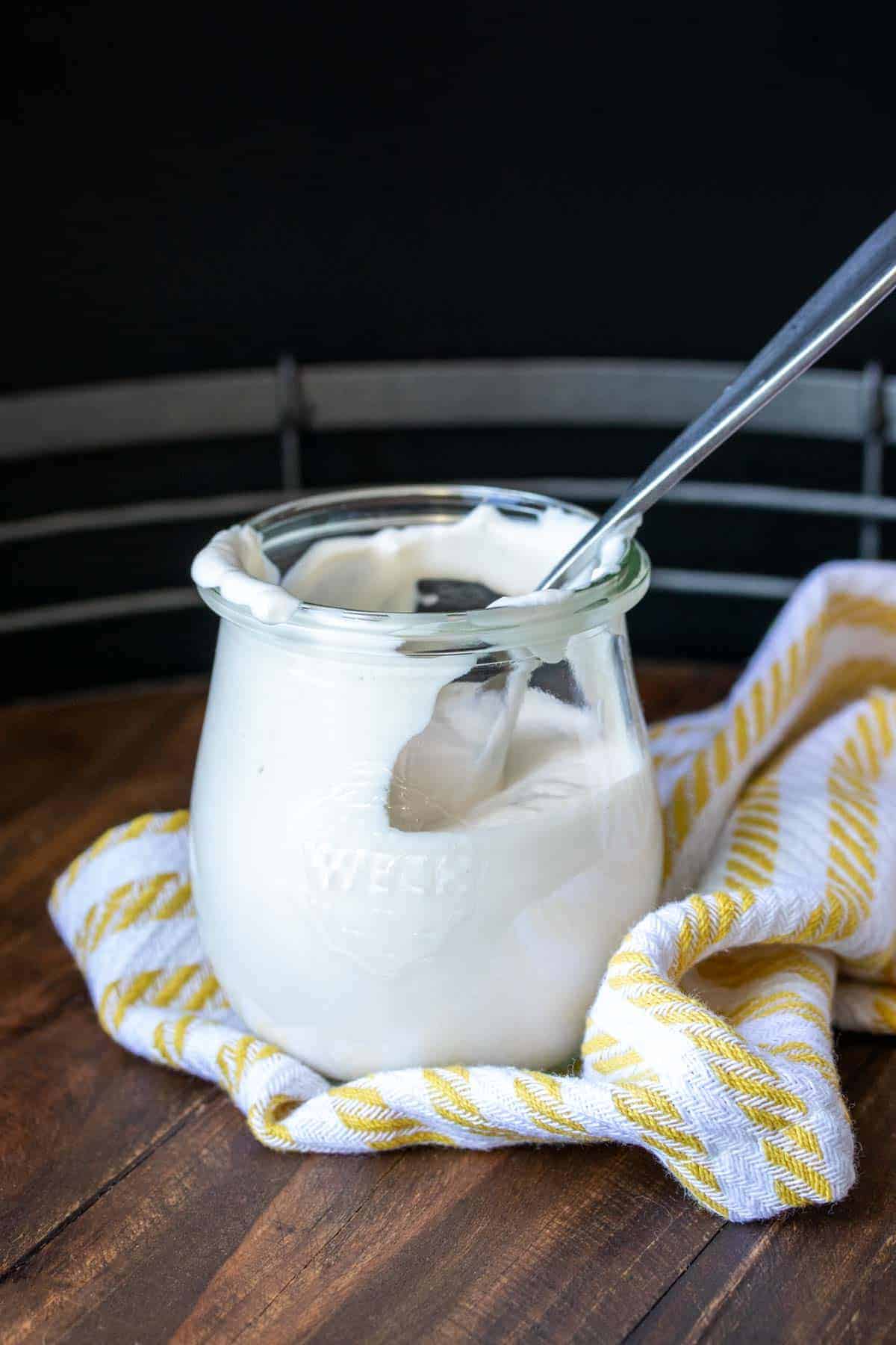 Spoon resting in a glass jar filled with sour cream