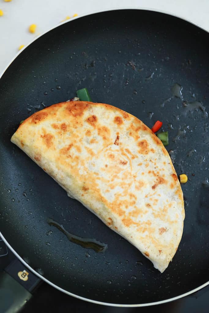 folded quesadilla cooking in a pan
