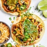 Black bean tostadas topped with corn, salsa, and veggies served on a white cutting board.