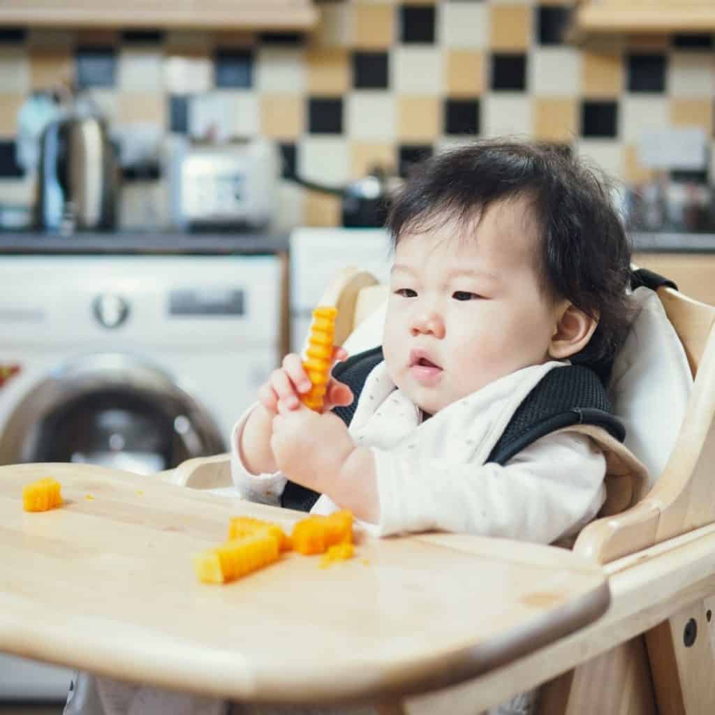 baby in high chair eating sliced butternut squash bites