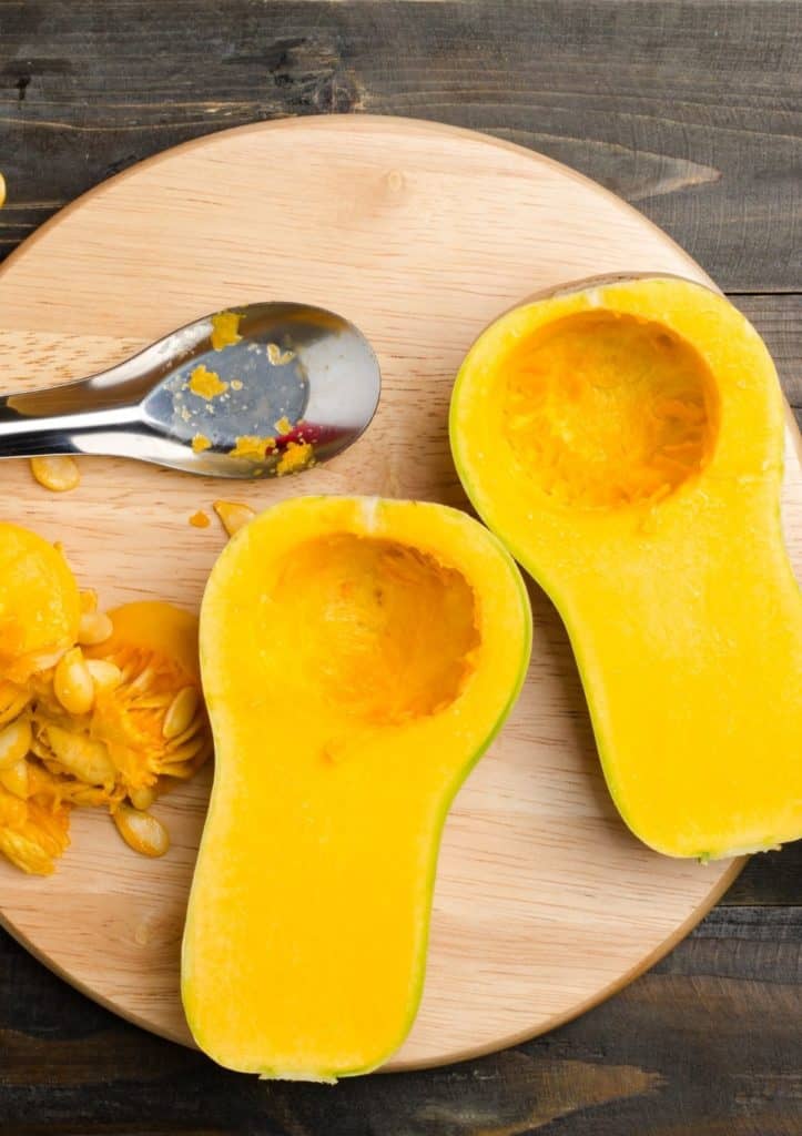 butternut squash cut in half with seeds removed on circular cutting board