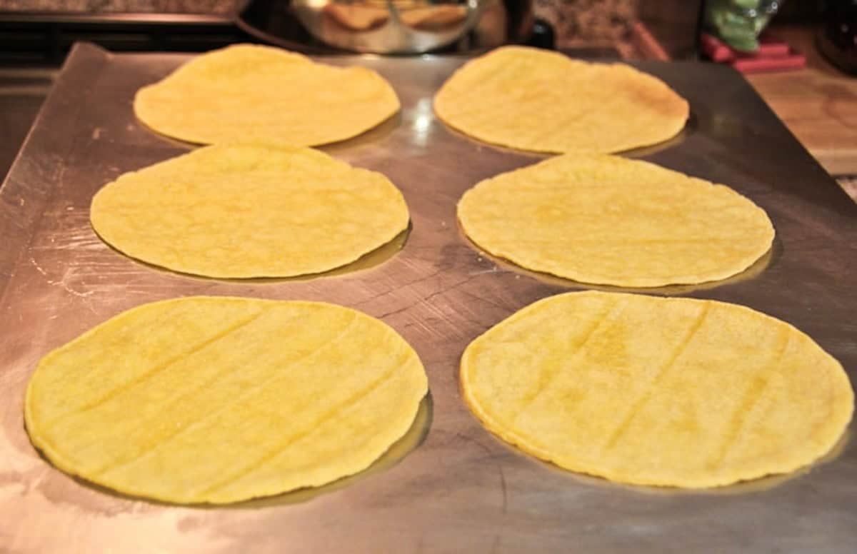 Corn tortillas on a baking sheet.