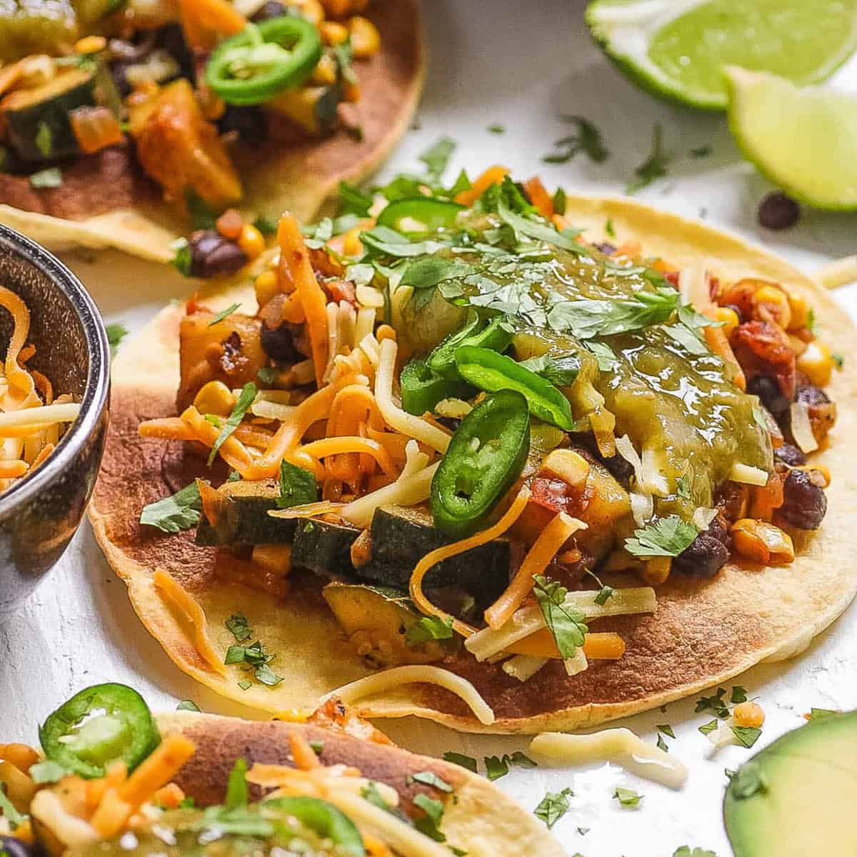 Black bean tostadas topped with corn, salsa, and veggies served on a white cutting board.