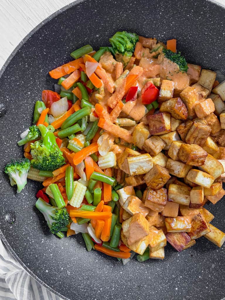 Frozen vegetables and tofu cooking in a wok.