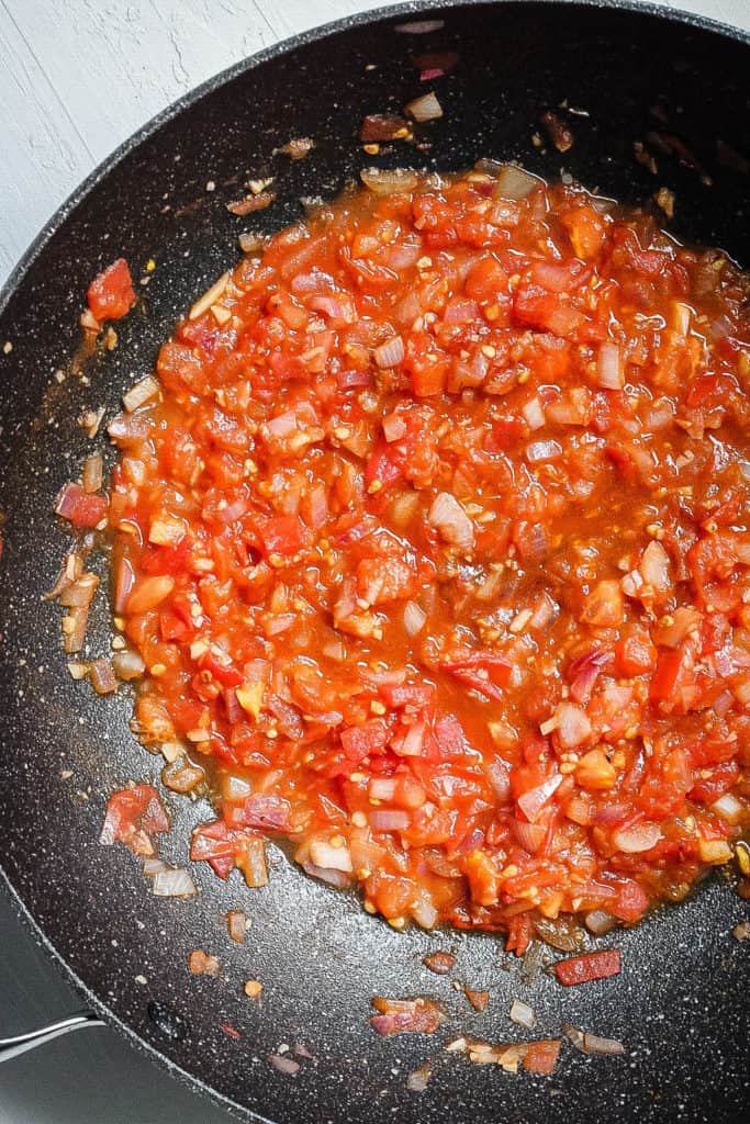 tomatoes and onions sauteeing in a pan