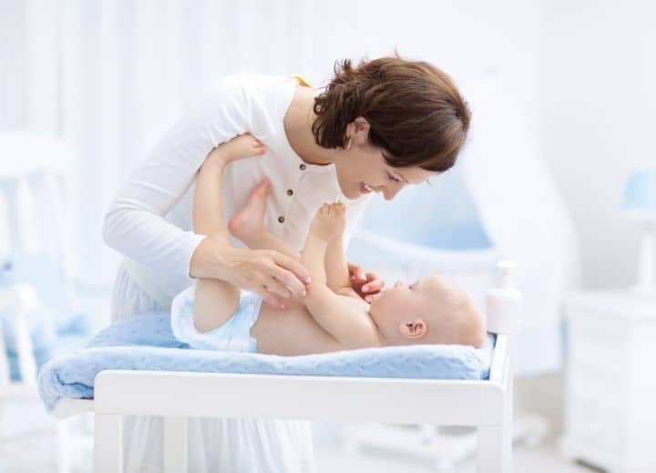 mom changing baby's diaper on changing table