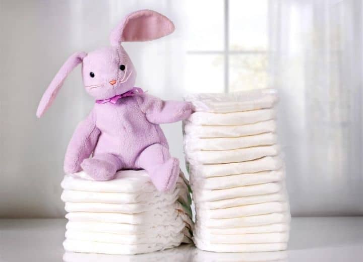 two stacks of white diapers with a stuffed purple rabbit on top