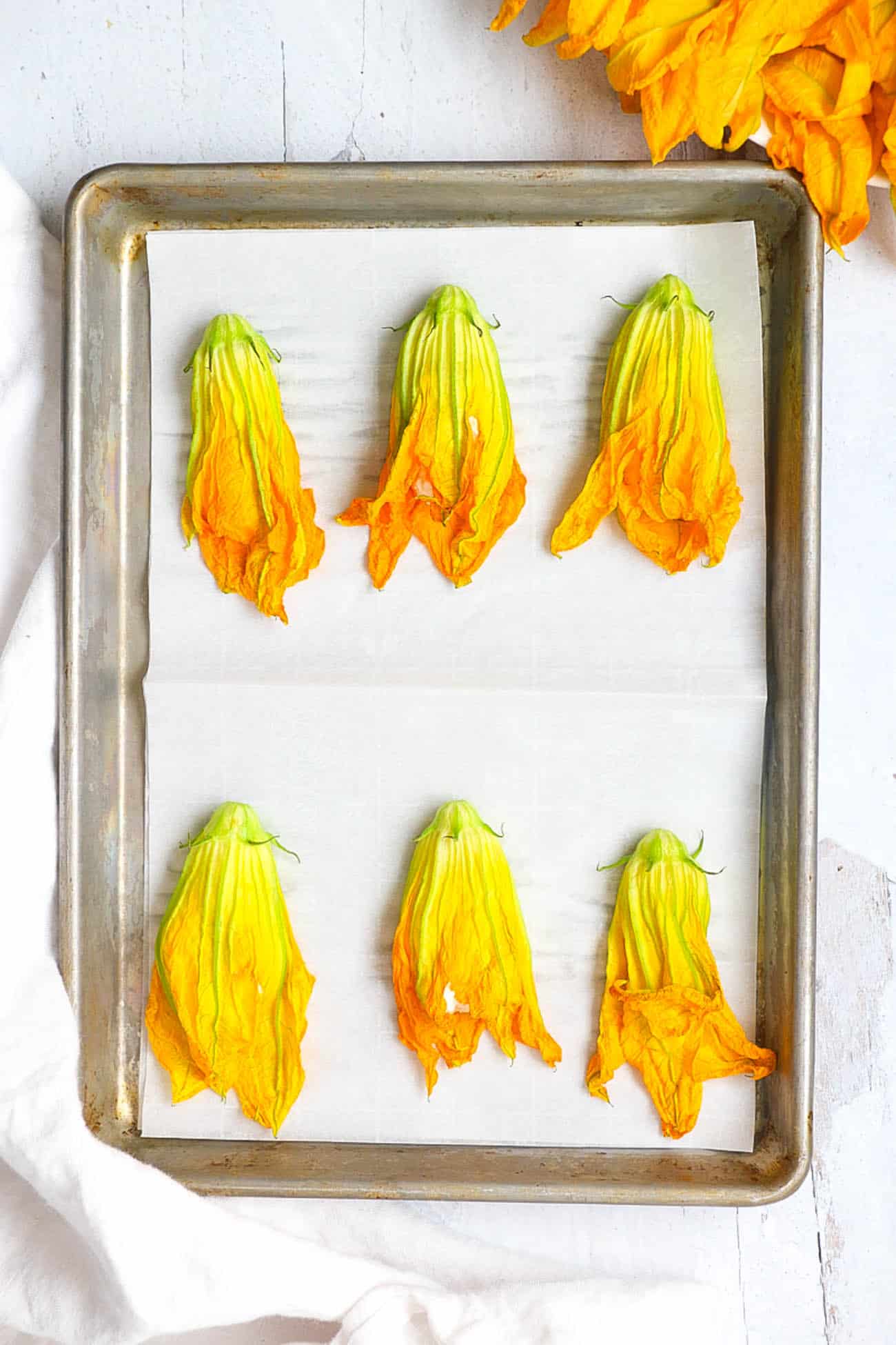 stuffed zucchini flowers on a baking sheet