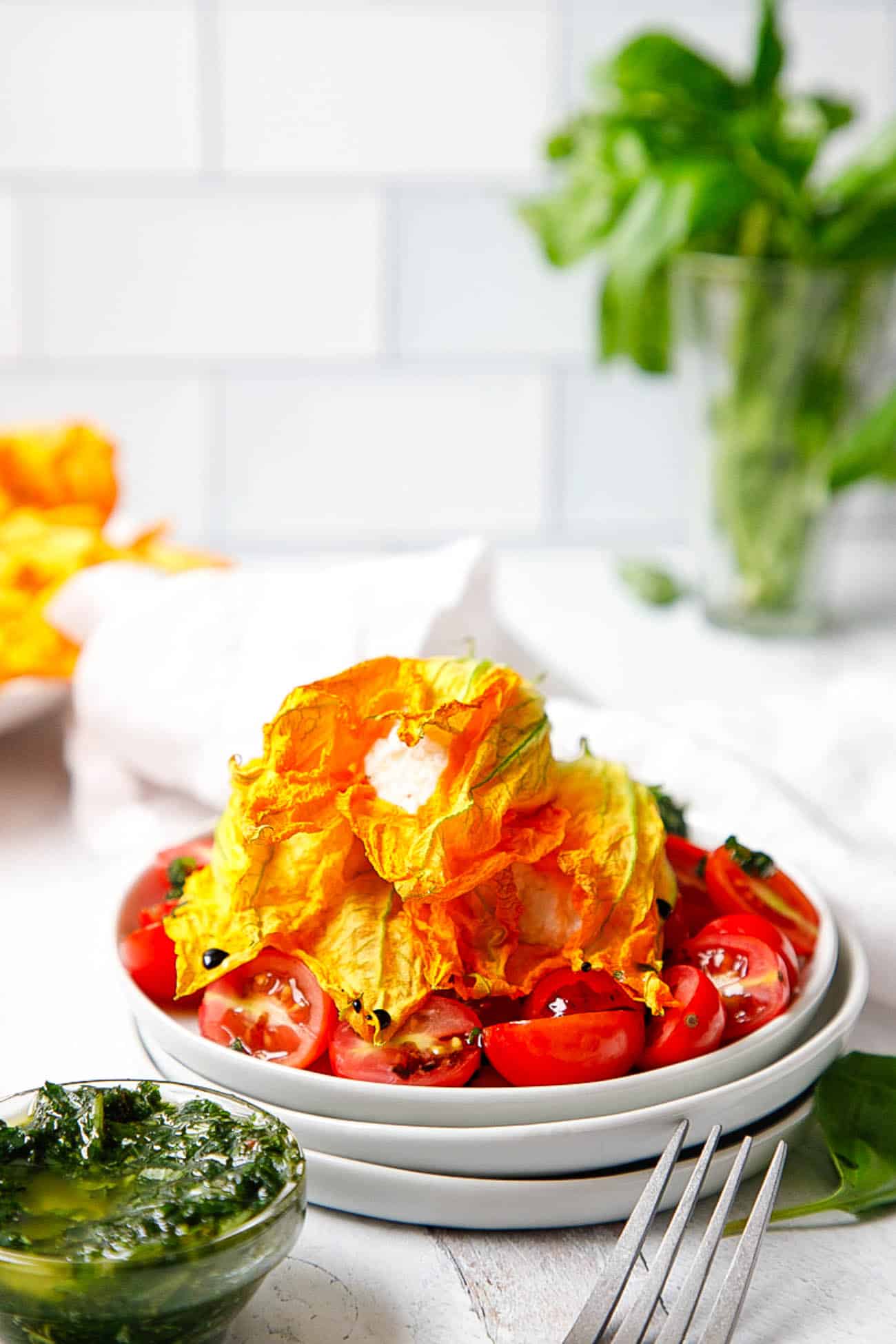 zucchini flowers stuffed with ricotta cheese, served on a bed of tomatoes, pesto, and balsamic vinegar