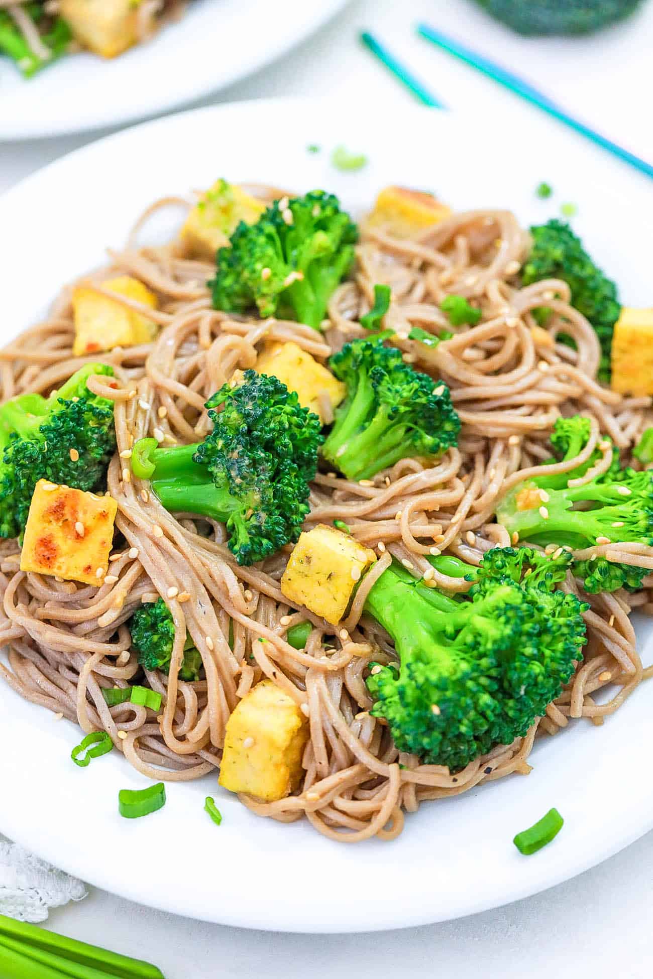 tofu and broccoli stir fry with sesame noodles on a white plate