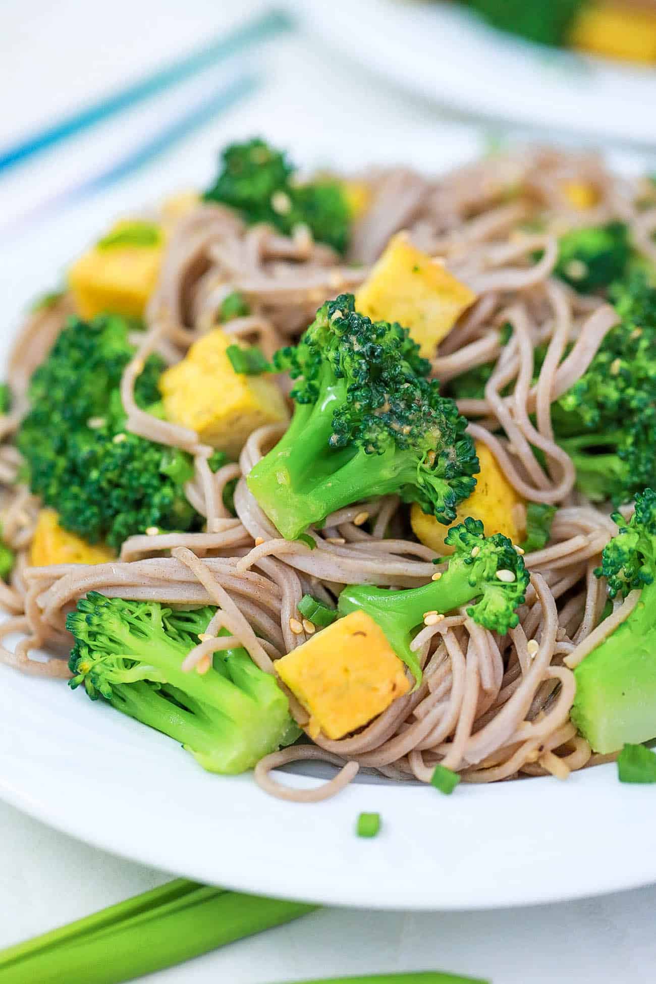 tofu and broccoli stir fry with sesame noodles on a white plate