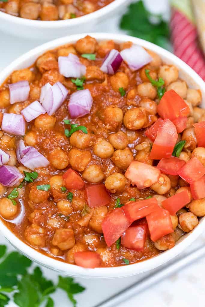 trader joe's channa masala recipe topped with tomatoes and onions, served in a white bowl